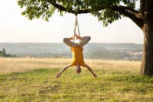 Aerial Yoga – Steffen in kopfüber hängender Position in Gurt am Baum