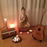 Harmonium und Gitarre im Yogastudio mit Kerzen und Bodhisattva-Figur