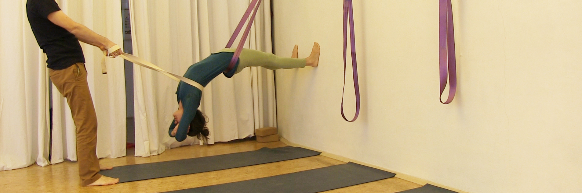 Yoga Übungen im Seil – intensive Rückbeuge im Gurt hängend mit zusätzlichem Gurtzug durch Partner